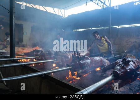 Spieß gebratene Schweine langsam über Holz- Glut in Talisay City, Cebu gekocht. Als "Lechon Baboy" in den Philippinen bekannt, einst gefeierten als "Das beste Schwein ever" von Starkoch, leider inzwischen verstorbenen, Anthony Bourdain. Als das Nationalgericht der Philippinen "Lechon baboy' ist einer der festen Favoriten mit Filipinos während des ganzen Jahres, besonders aber bei besonderen Veranstaltungen wie Geburtstage, Feste und Weihnachten, wo buchstäblich Hunderte von Tausenden von Schweinen geröstet werden. Der Provinz Cebu ist als das beste Lechon in den Philippinen. Händler der Gattungen haben ihre eigenen eng g Stockfoto