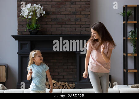 Glückliche junge Mutter tanzen mit kleinen Tochter zu Hause Stockfoto