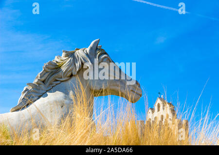 Saintes-Maries-de-la-Mer, Frankreich - 27 September 2019: Insbesondere der Pferd Statue mit Die befestigte Kirche im Hintergrund Stockfoto