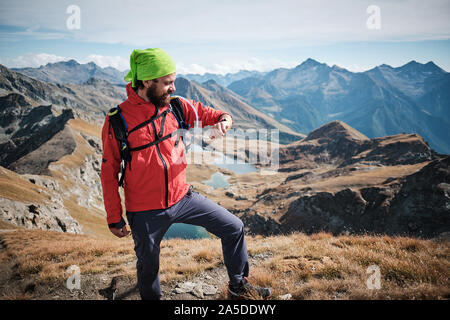 Junger Mann auf der Suche an der GPS-Track auf seinem tragbaren, beim Wandern in den Bergen in einem klaren Herbsttag Stockfoto