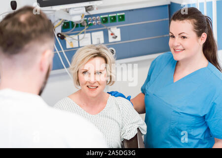 Patienten im Aufwachraum der Klinik im Gespräch mit Arzt Stockfoto