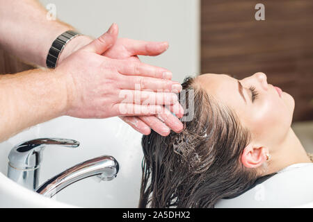 Professionelle Friseur ist das Waschen der Haare im Waschbecken vor dem Schneiden an Barbershop. Friseur Salon, weiblichen stylist Konzept. Stockfoto