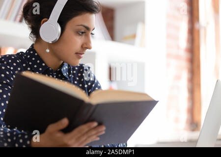 Indische Frau bereiten Essay mit Lehrbuch und Internet online Web site Stockfoto