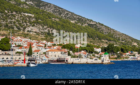 Bol Hafen Pier mit Stadt gegen Insel Hügel, Brac, Kroatien gesetzt. Stockfoto