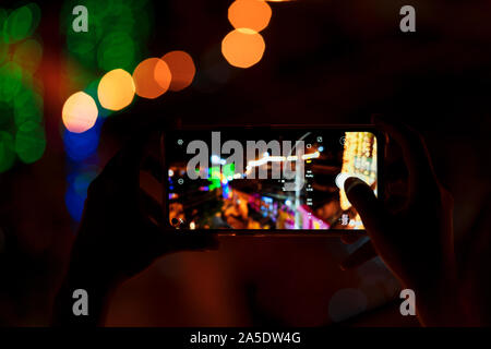 Person, die smart phone & Erfassung Foto von festlichen Dekorationen in der Nacht. Hintergrundbild für Street mobile Fotografie, Diwali feiern. Stockfoto