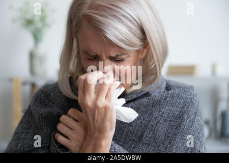 Kranke reife Frau mit Decke blasen laufende Nase Niesen abgedeckt Stockfoto