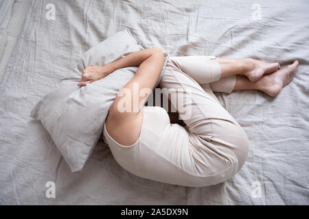 Erschrocken reife Frau liegend auf Bett fetalen Position decken Kissen Stockfoto