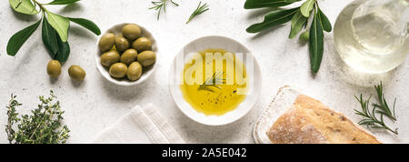 Olivenöl. Bio Olivenöl in Schüssel mit grünen Oliven, Kräuter, Gewürze und Ciabatta Brot auf weißem Hintergrund, Banner, typisch mediterrane Küche con Stockfoto
