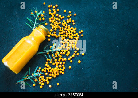 Flasche Sanddorn vitamin Saft und frischen Sanddornbeeren auf schwarzem Hintergrund. Ansicht von oben, kopieren. Stockfoto