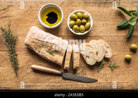 Ciabatta - Frische hausgemachte italienische Brot, Oliven und Olivenöl auf Holztisch, Ansicht von oben. Stockfoto