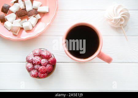 Lebende Koralle Farbe Schale und Platte auf weißem Hintergrund. Coconut Stücke und Himbeere 'start und Merengue, Ansicht von oben. Stockfoto