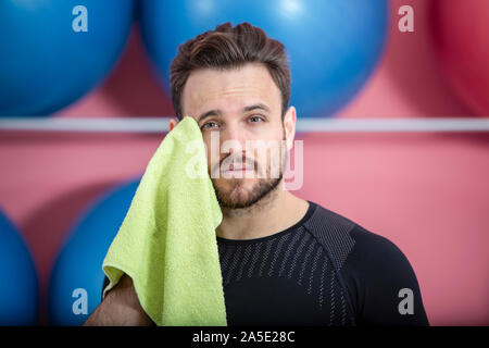 Porträt einer passen müde Mann sein Gesicht wischen mit einem Handtuch in der Turnhalle während der Ausbildung Stockfoto