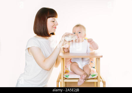 Eine junge schöne Mutter Feeds ein Baby aus einer Flasche. Stockfoto