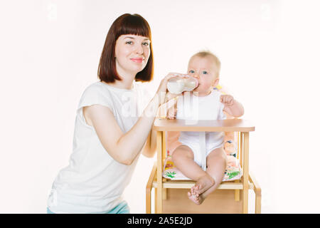 Eine junge schöne Mutter Feeds ein Baby aus einer Flasche. Stockfoto