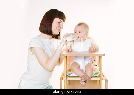 Eine junge schöne Mutter Feeds ein Baby aus einer Flasche. Stockfoto