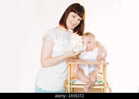 Eine junge schöne Mutter Feeds ein Baby aus einer Flasche. Stockfoto