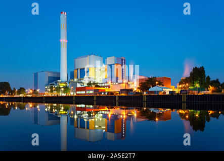 Eine bunte industrielle Gebäude an einem Kanal mit sauber Reflexion und Nacht blauer Himmel. Stockfoto