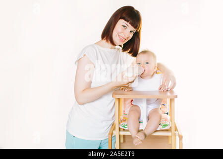 Eine junge schöne Mutter Feeds ein Baby aus einer Flasche. Stockfoto