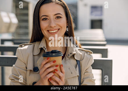 Kaffeepause. Gerne Mädchen zeigen ihr Lächeln während Erwärmung ihre Hände beim Spaziergang Stockfoto