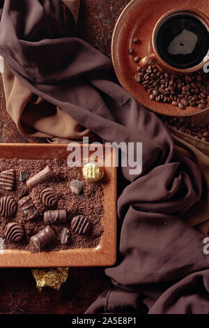 Pralinen, Schokolade, Chips und Kaffee auf einem alten, braunen Tisch. Ansicht von oben. Stockfoto