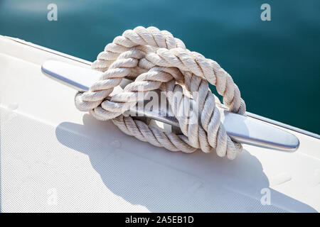 Edelstahl Anlegestellen Klampe mit geknoteten Seil auf der weißen Yacht Deck montiert Stockfoto