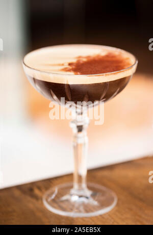 Dunkler Cocktail Espresso martini dekoriert mit Kakao auf Holzoberfläche Bei Tageslicht Stockfoto