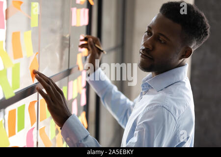 Schwere afrikanische amerikanische Geschäftsleute Verwaltung Projekt Aufgaben auf Haftnotizen Stockfoto