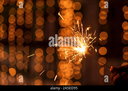 Diwali urlaub Grußkarte, Postkarte. Eine junge Frau mit beleuchteten Feuerwerk mit hellen goldene Weihnachten bokeh leuchtet. Hintergrundbild für Diwal Stockfoto