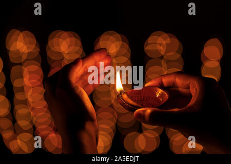 Indisches Mädchen oder Frau Holding oder Schutz der traditionellen Lehm diya oder öl Lampe auf Diwali Feier mit Kopie Raum auf schwarzem Hintergrund isoliert. Stockfoto