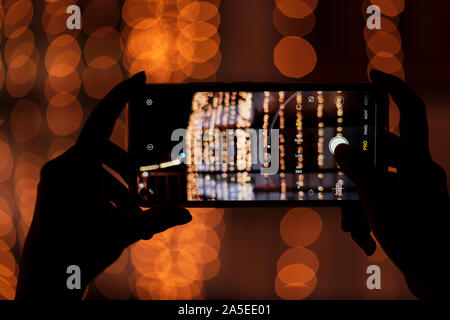 Person, die smart phone & Erfassung Foto von festlichen Dekorationen in der Nacht. Hintergrundbild für Diwali Festival, Straße mobile Fotografie. Stockfoto