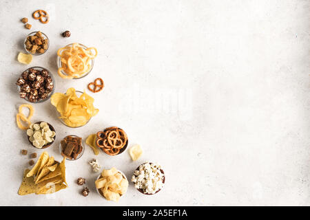 Satz von ungesunden Snacks: chips, Popcorn, nachos, Brezeln, Zwiebelringe in Schalen, Ansicht von oben, kopieren. Ungesunde Ernährung Konzept, Sortiment Snacks für Stockfoto