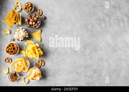 Sortiment ungesunden Snacks: chips, Popcorn, nachos, Brezeln, Zwiebelringe in Schalen, Ansicht von oben, kopieren. Ungesunde Ernährung Konzept, Snacks für Einstellen Stockfoto