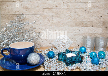 Heißer Kakao mit der Milch in blauer Schale. Silber und Blau Weihnachtsschmuck, wie Silber Perlen und Weihnachtskugeln. Türkis und Silber Kerzenständer. Stockfoto