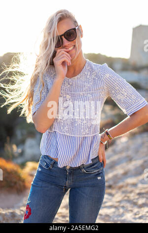 Gerne natürliche blonde Frau in Sonnenbrille posiert im Freien Stockfoto