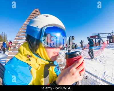 Frau in Ski Maske und Helm Trinkwasser warm up Tee auf der Spitze des Hügels Stockfoto