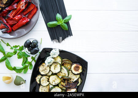 Italienische Küche, gegrilltes Gemüse und Pasta roh schwarz auf weiß Holz- rustikalen Tisch. Platz für Text. Kopieren Sie Platz. Stockfoto