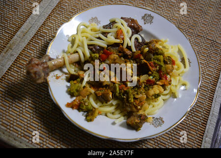 Geschmorte Bein einer hausgans mit überprüften Ukrainischen Nudeln und gewürzt mit Gemüse von Auberginen, Möhren, Zwiebeln und Brokkoli. Stockfoto