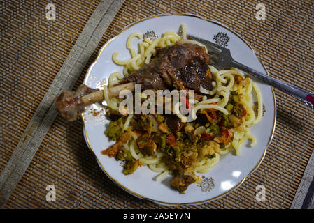 Geschmorte Bein einer hausgans mit überprüften Ukrainischen Nudeln und gewürzt mit Gemüse von Auberginen, Möhren, Zwiebeln und Brokkoli. Stockfoto