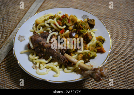 Geschmorte Bein einer hausgans mit überprüften Ukrainischen Nudeln und gewürzt mit Gemüse von Auberginen, Möhren, Zwiebeln und Brokkoli. Stockfoto