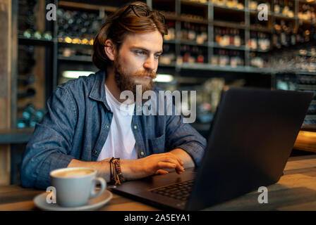 Junge konzentriert bärtigen Geschäftsmann von einem Laptop in einem Cafe arbeiten Stockfoto