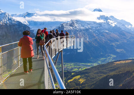 Grindelwald, Schweiz - Oktober 10, 2019: Leute die Bilder auf Sky Cliff Walk Metal Bridge auf den ersten Gipfel der Schweizer Alpen Berge, Schnee, Gipfel Pano Stockfoto