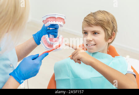 Weibliche Zahnarzt ihre jungen Patienten wie zu reinigen Zähne richtig angezeigt Stockfoto