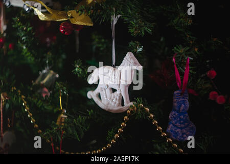 Weihnachten Spielzeug in Form einer weißen Keramik antik Schaukelpferd mit Geschenken auf einem geschmückten Weihnachtsbaum. Close-up. Stockfoto