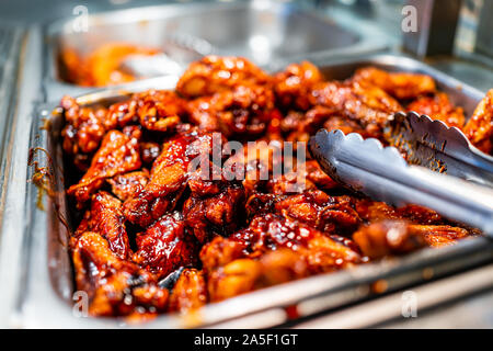 Barbeque sauce Chicken wings Buffet Selbstbedienung mit Zangen in Lebensmittelgeschäft, Restaurant oder Catering Event mit roter Farbe ungesunde Nahrung Stockfoto