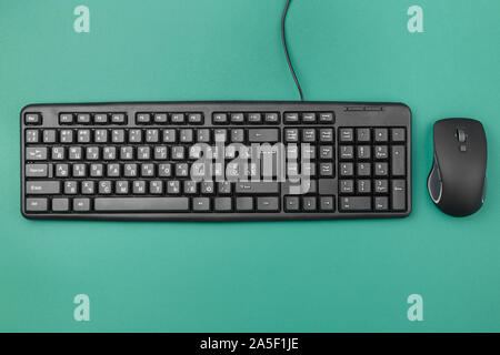 Tastatur für Computer mit einem Kabel auf dem Tisch. In der Nähe liegt eine kabellose Maus. Moderne Bürogeräte Stockfoto