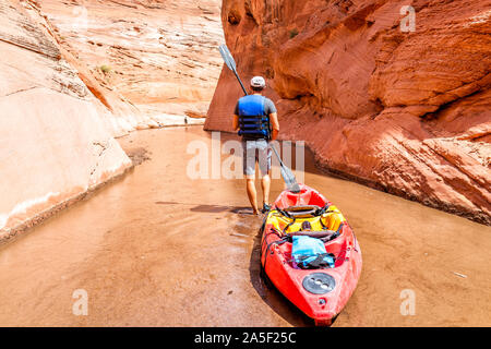 Kajak Trail im Lake Powell Antelope Canyon mit schmalen Mann holding Paddel Ruder ziehen Kajak Boot zu tieferen schmutzige schlammige Wasser Stockfoto