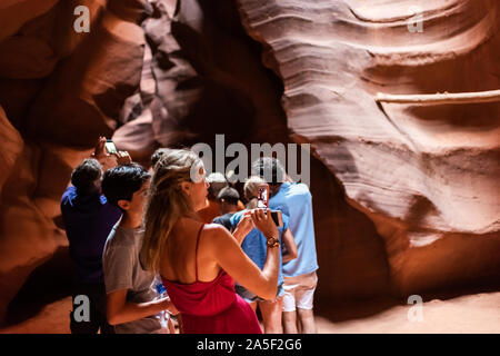 Seite, USA - 10. August 2019: Tour Gruppe der jungen Frau in Upper Antelope Slot Canyon in Arizona Fotos mit Telefon aus Sandstein für Stockfoto