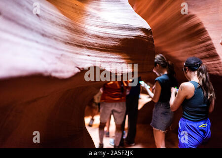 Seite, USA - 10. August 2019: Tour Gruppe junger Menschen zu Fuß auf den Weg in Upper Antelope Slot Canyon in Arizona und abstrakte Sandstein Bildung Stockfoto