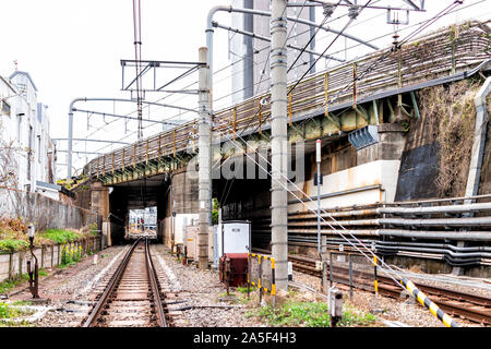 Tokyo, Japan - 28. März 2019: Shinjuku Straße Straße durch Gebäude während des Tages mit Bahnübergang Bahnhof Titel Überführung mit vielen industriellen Kabel ca Stockfoto