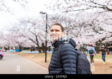Tokio, Japan Yoyogi Park mit glücklichen jungen Touristen Mann zu Fuß auf der Straße Straße weg von Sakura Blumen rosa weiß Cherry Blossom Bäume Stockfoto